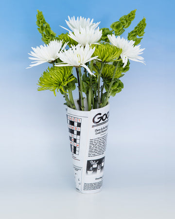 rolled newspaper shaped vase with white flowers inside