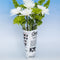 rolled newspaper shaped vase with white flowers inside