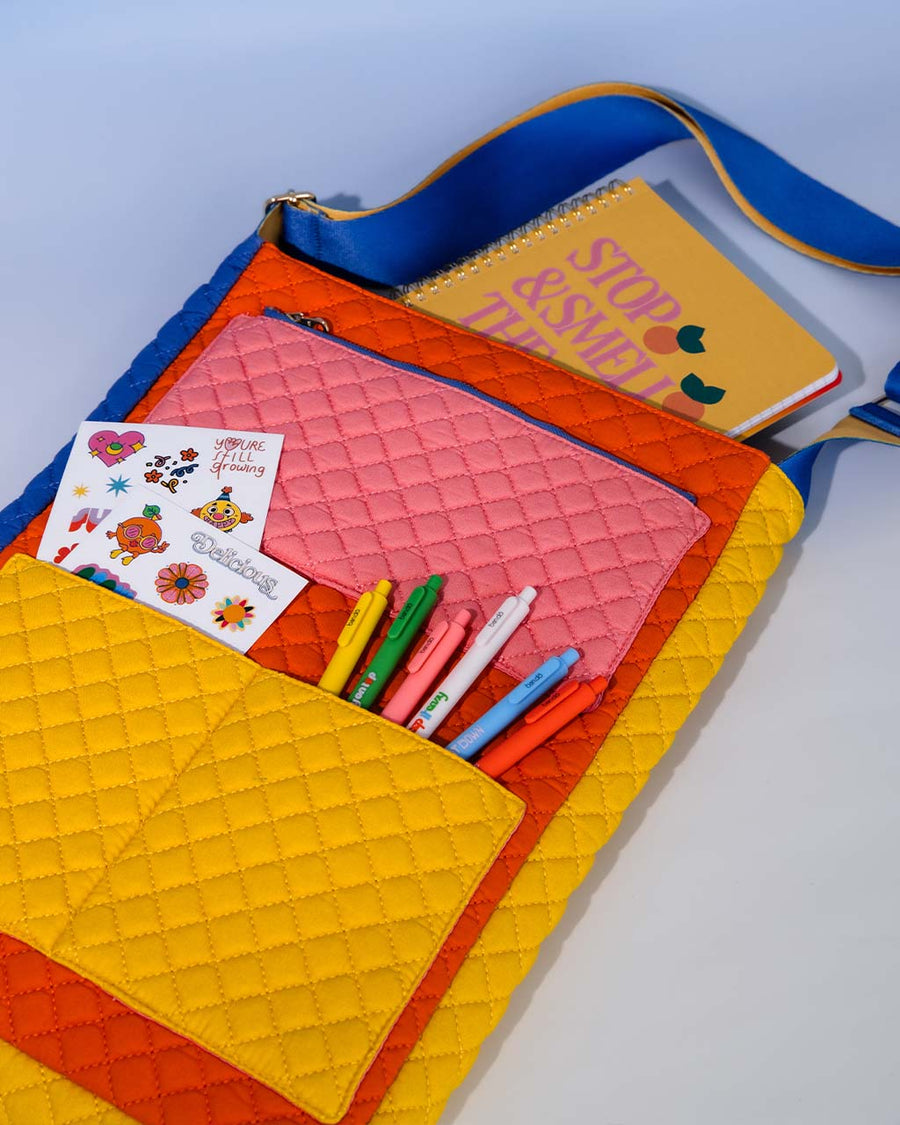 pink, yellow, red, and blue quilted laptop tote with various items in its pockets
