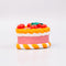 side view of ceramic pink cake shaped ornament with orange and white trim and 'cherries on top' 