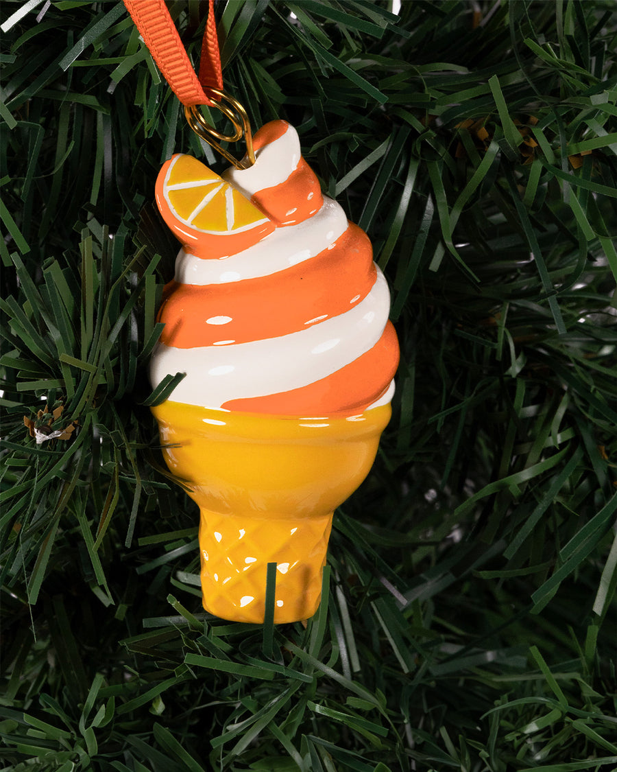 ceramic orange and white swirled ice cream cone ornament on a tree