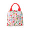 back view of light pink lunch tote with all over cherry and flower print and red handles