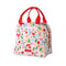 side view of light pink lunch tote with all over cherry and flower print and red handles