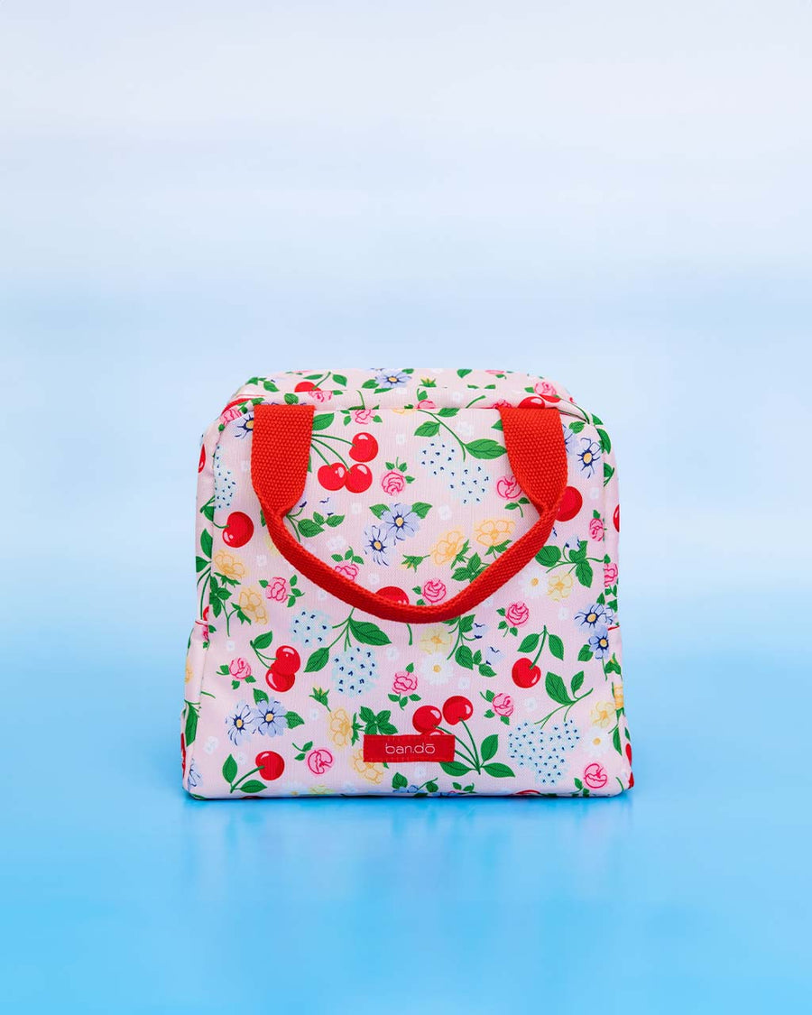 light pink lunch tote with all over cherry and flower print and red handles