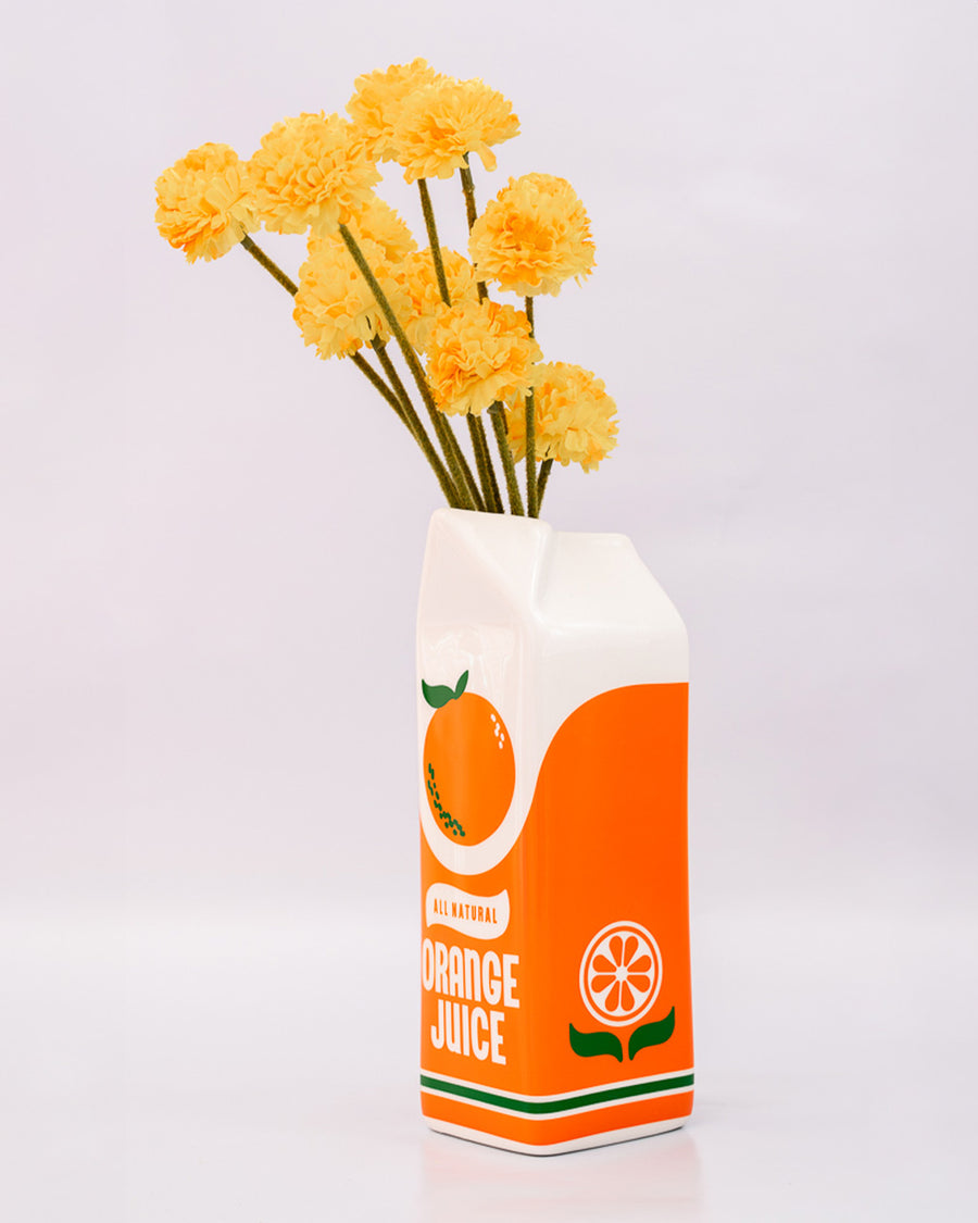 side view of Porcelain orange juice carton-shaped vase with flowers inside