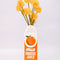 front view of Porcelain orange juice carton-shaped vase with flowers inside