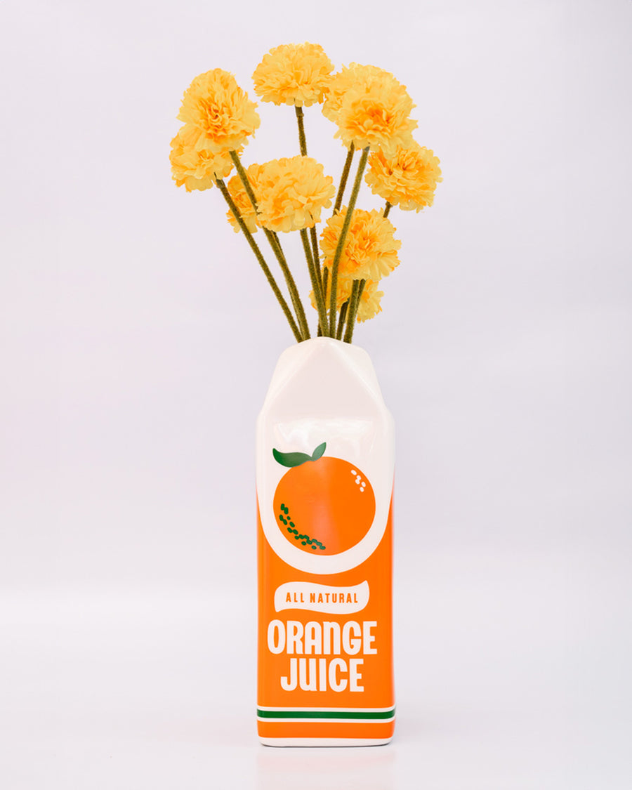 front view of Porcelain orange juice carton-shaped vase with flowers inside