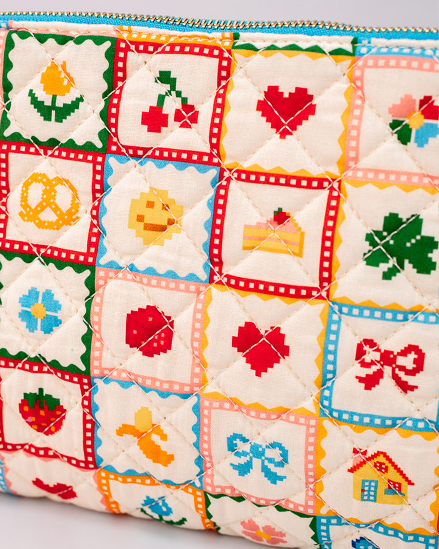 up close of white quilted pouch with various hearts, fruits, smiley faces