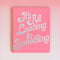 pink large notebook with white 'it's all leading to something' typography across the front