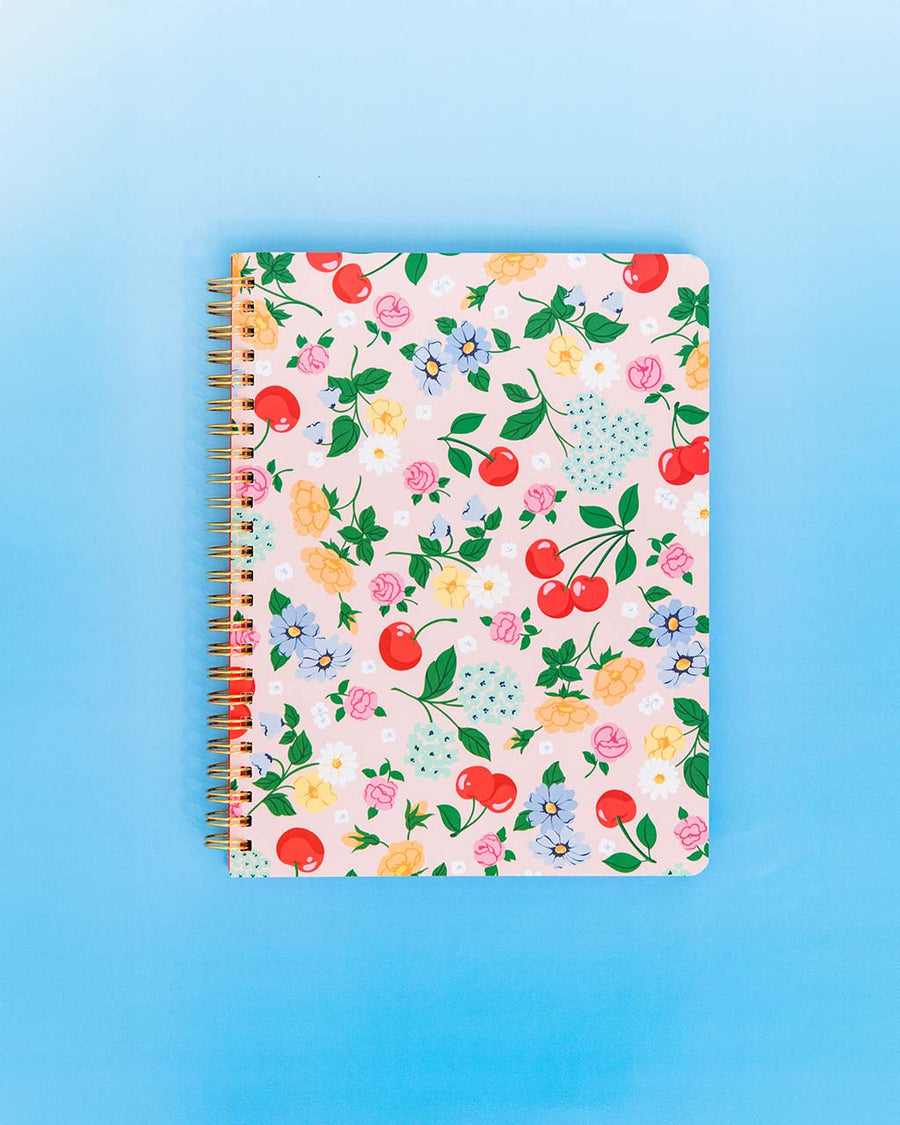 light pink mini notebook with cherry and floral print on blue background