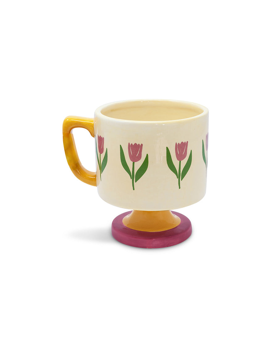 top view of cream 10 oz ceramic mug with yellow handle, pink pedestal base and pink tulip print