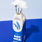 white and blue carton shaped ceramic vase with 'organic oat milk' across the front with white flowers inside