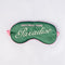 dark green sleep mask with pink and white embroidered 'greeting from paradise' with pink adjustable strap