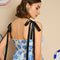 up close of model wearing white/light blue midi dress with ruffle hem, black tie straps and all over blue flower print