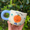 model holding white mug with periwinkle handle with 'yee-haw' orange on it