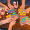 Four sets of hands holding playing cards at a table with drinks