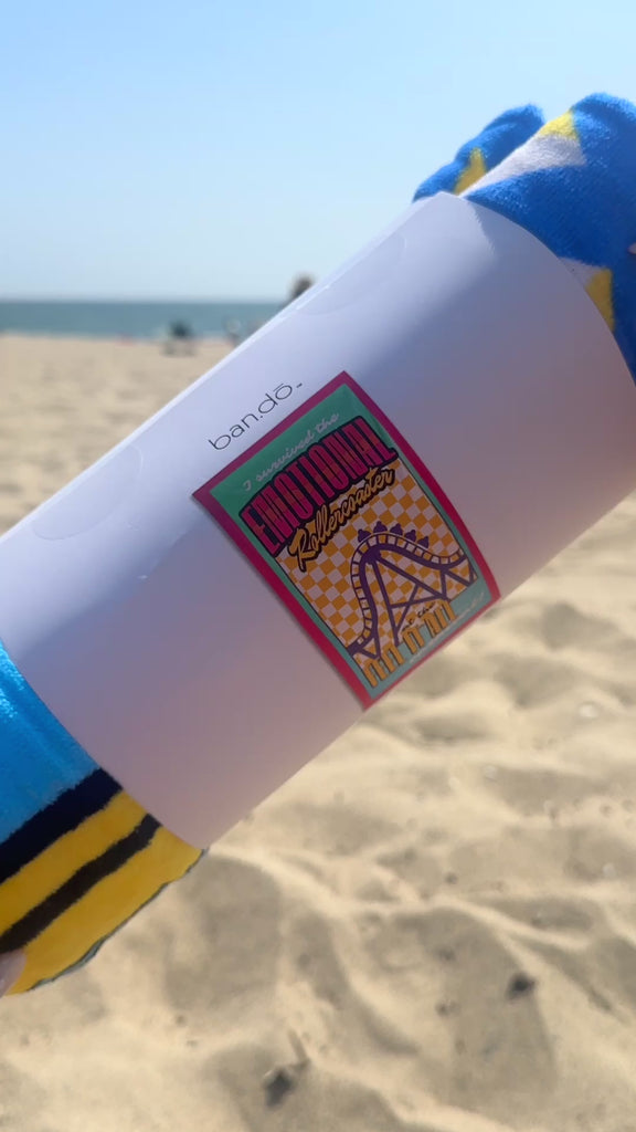 model unrolling giant 'emotional rollercoaster' beach towel on the beach