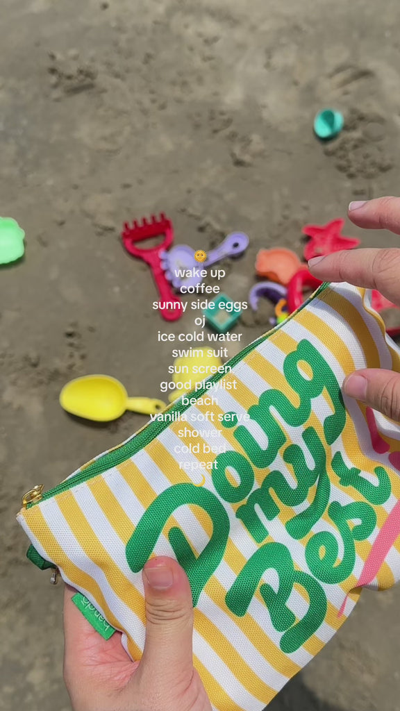 model using small yellow and white stripe 'doing my best' pouch at the beach