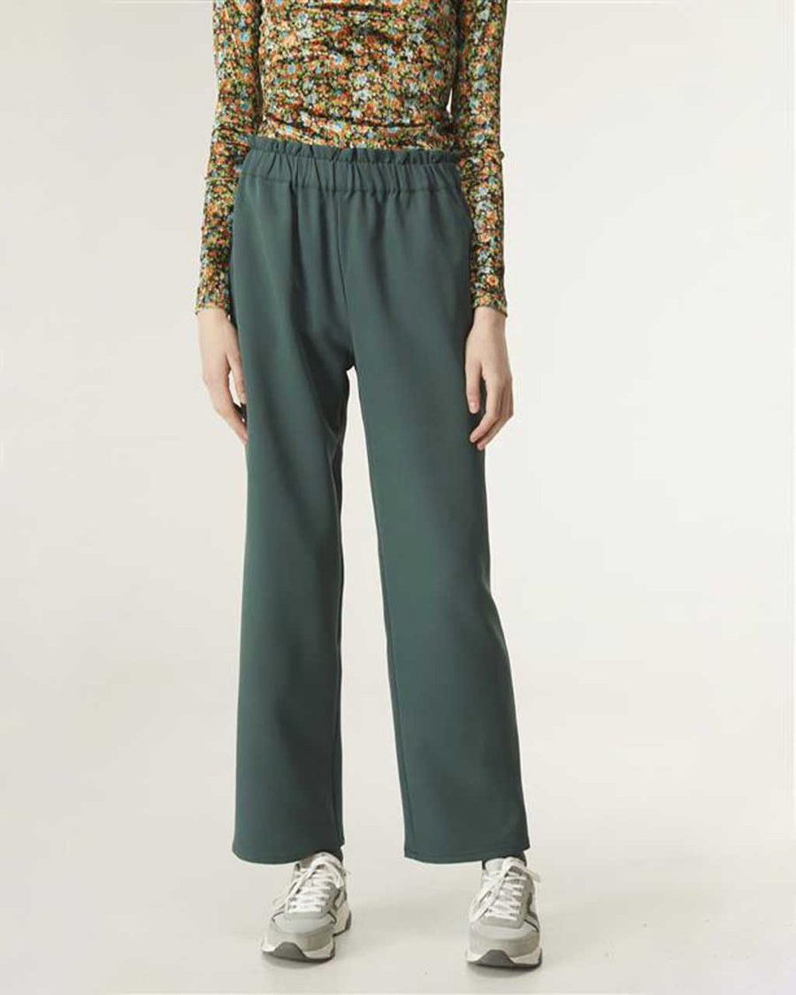 model wearing green elastic trousers with print top and sneakers