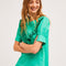 model wearing green ruffle-front blouse with eyelet detail and blue jeans