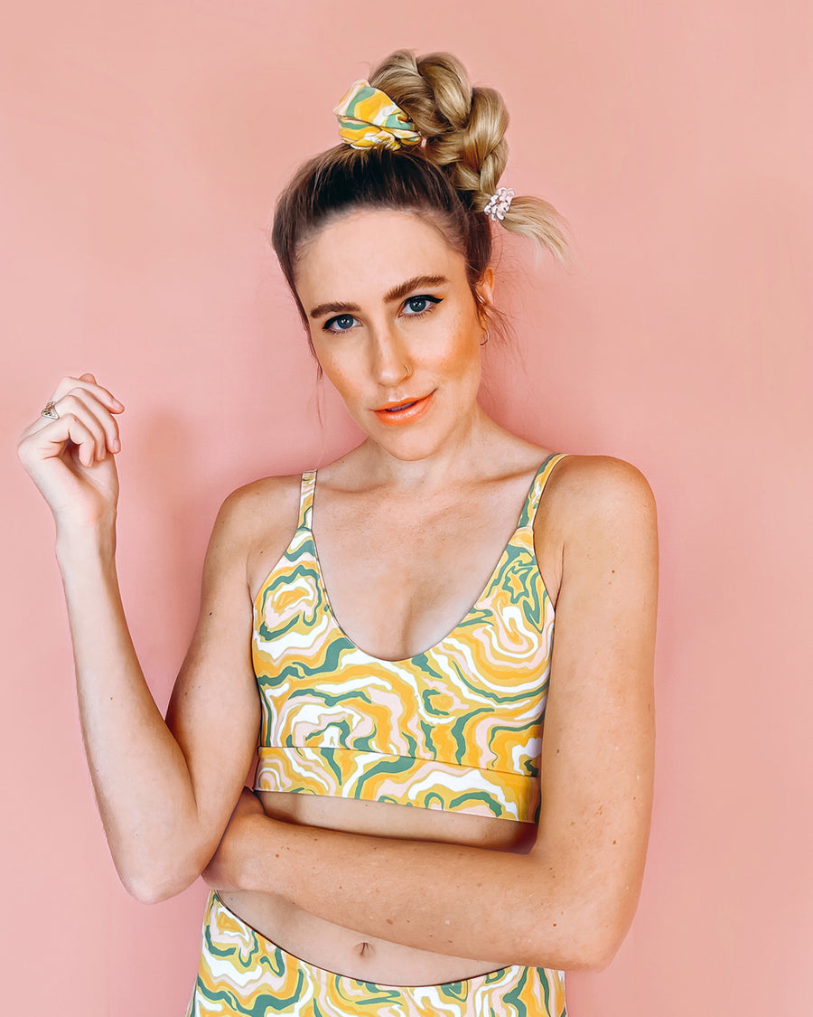 model wearing yellow swim suit with green and pink swirl floral print