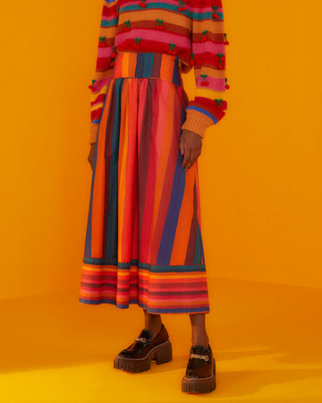 model wearing multicolor vertical and horizontal stripe midi skirt with stripe cherry sweater and black platform shoes