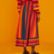 back view of model wearing multicolor vertical and horizontal stripe midi skirt with stripe cherry sweater and black platform shoes