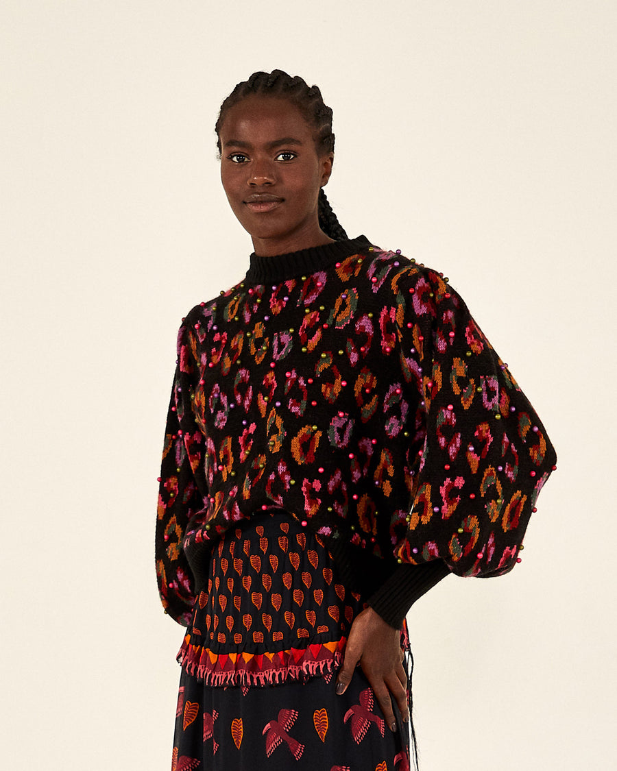 model wearing black ikat leopard sweater with multicolored pearl embellishments with black printed pants