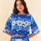 model wearing blue and white applique cropped top with flutter sleeves and matching skirt