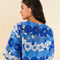 backview of model wearing blue and white applique cropped top with flutter sleeves and matching skirt with keyhole back