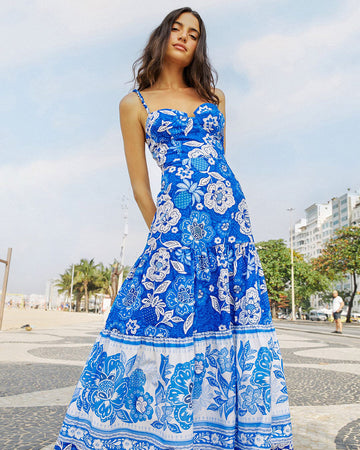 model wearing blue and white abstract floral tiered midi dress with unique strap detail