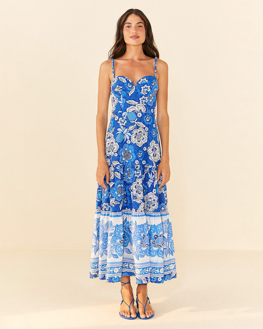 model wearing blue and white abstract floral tiered midi dress with unique strap detail