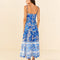 backview of model wearing blue and white abstract floral tiered midi dress with unique strap detail