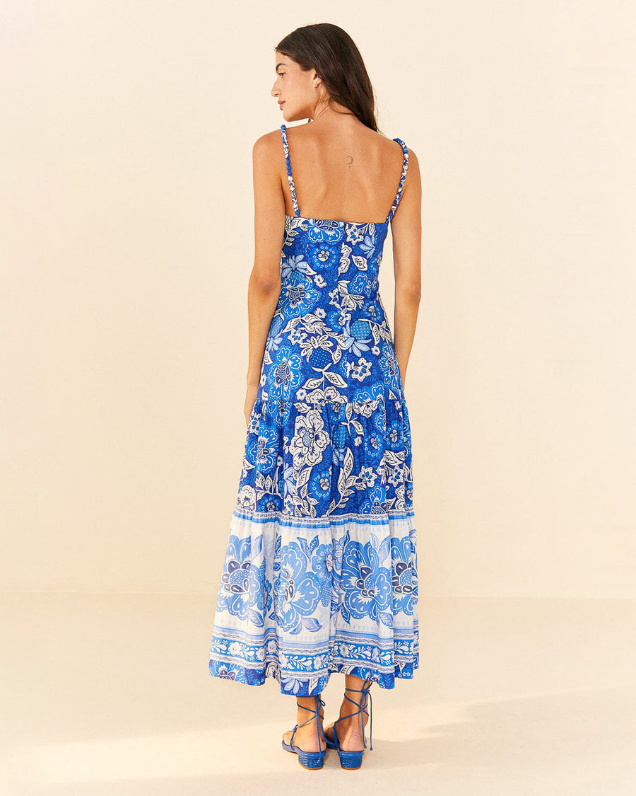 backview of model wearing blue and white abstract floral tiered midi dress with unique strap detail