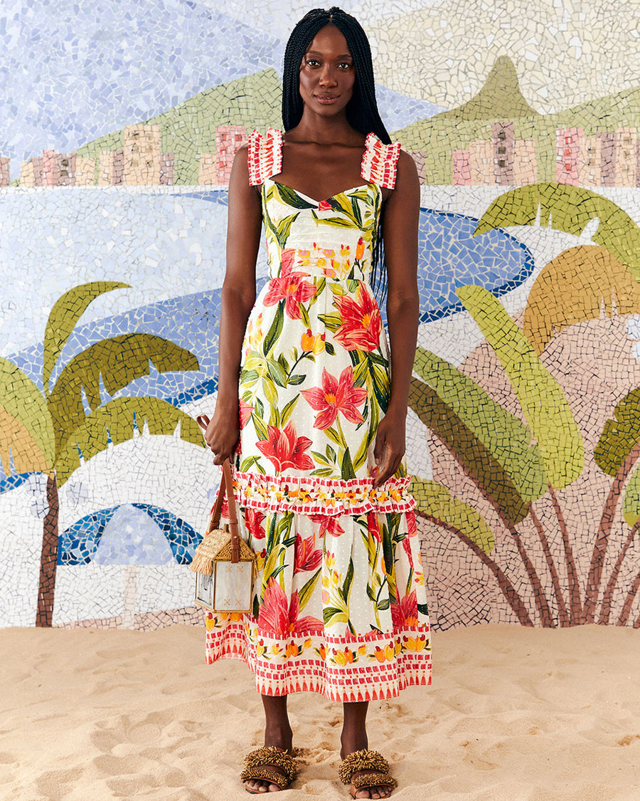 frontview of model wearing white midi dress with large all over red flower print, ruffle tank straps, tiered ruffle skirt and cinched bodice