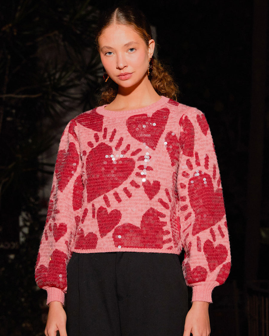 model wearing pink cropped sweater with all over sequins and graphic heart print