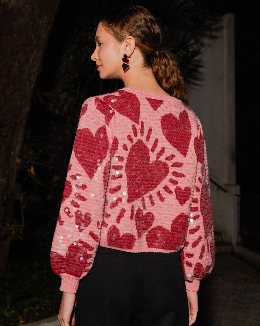 backview of model wearing pink cropped sweater with all over sequins and graphic heart print