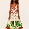 model wearing white maxi dress with various different multicolor prints, fruit charms on straps and deep v neckline