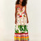 model wearing white maxi dress with various different multicolor prints, fruit charms on straps and deep v neckline