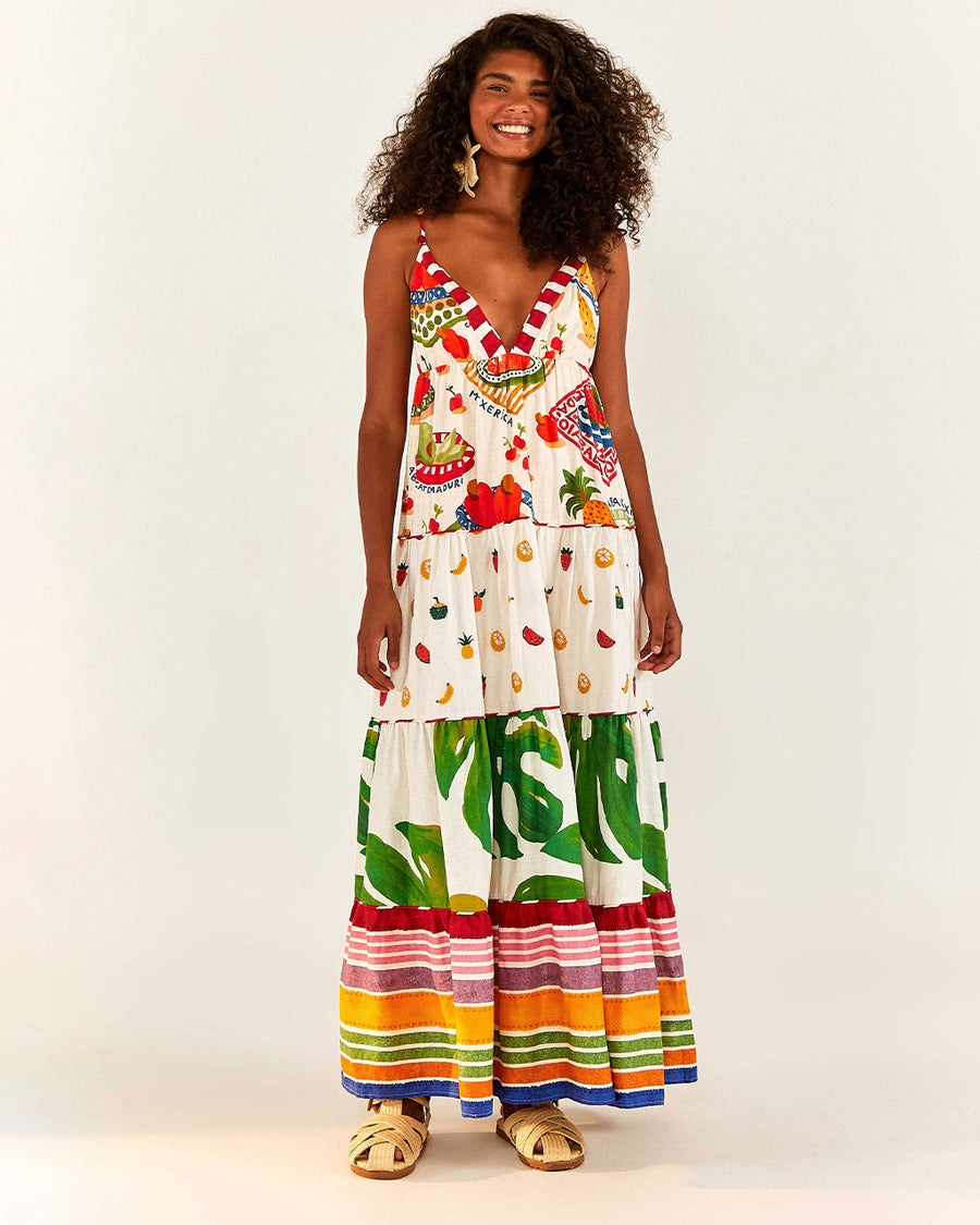 model wearing white maxi dress with various different multicolor prints, fruit charms on straps and deep v neckline