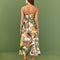 backview of model wearing white midi sundress with vibrant forest leaf print and back smocking