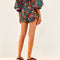 backview of waist down of scalloped hem shorts with black ground and all over multi wildflower print