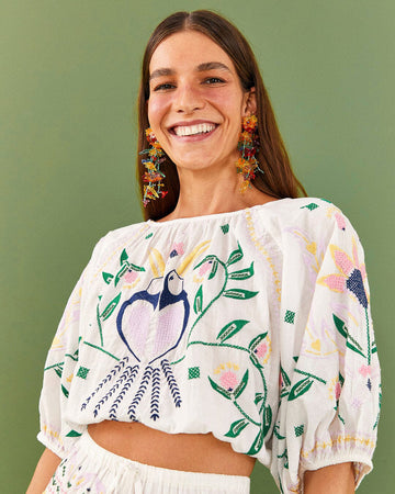 model wearing crop white cotton top with colorful embroidered flower and macaw print