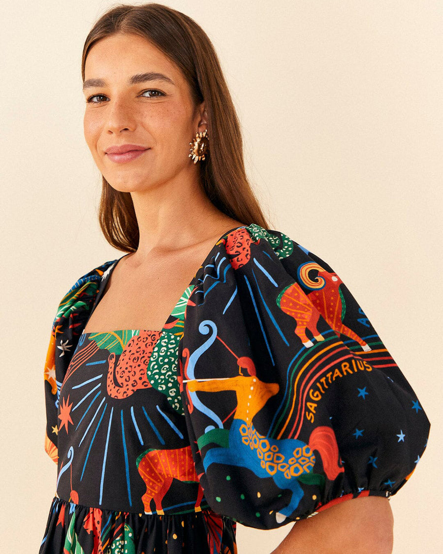 up close of model wearing navy mini dress with vibrant zodiac sign graphics and short puff sleeves