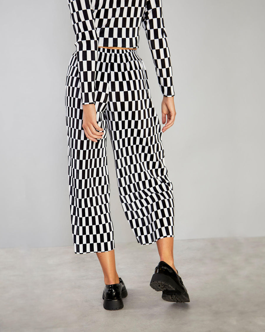 back-view of model wearing black and white checked cropped pants, black and white checkered top and black shoes