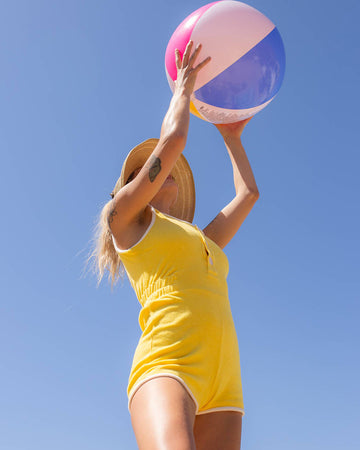 model wearing yellow terry cloth romper with white trim accents