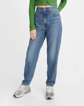 model wearing tapered high waist denim, green shirt and sneakers