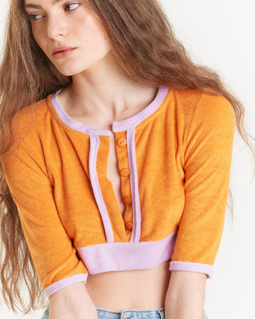 model wearing terry cloth cropped cardigan with orange ground and lilac trim