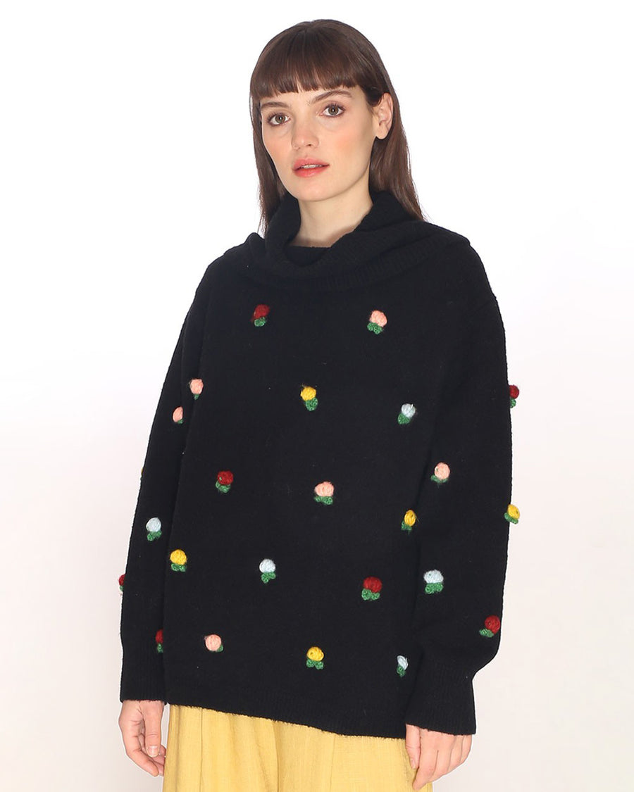 model wearing black turtleneck sweater with colorful flowers throughout