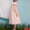 sideview of model wearing light pink flowy midi dress with flutter sleeves and textured flower design